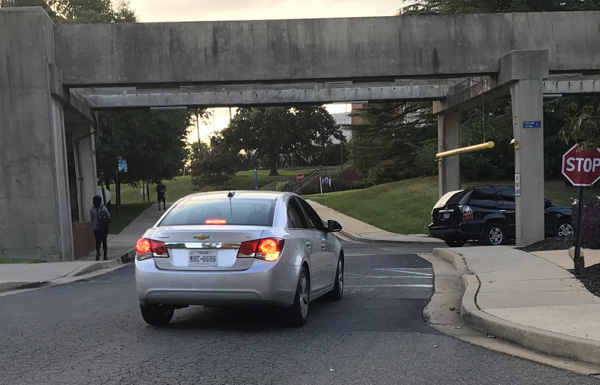 picture shows the crosswalk next to the stop sign, with a driver waiting at the stop sign